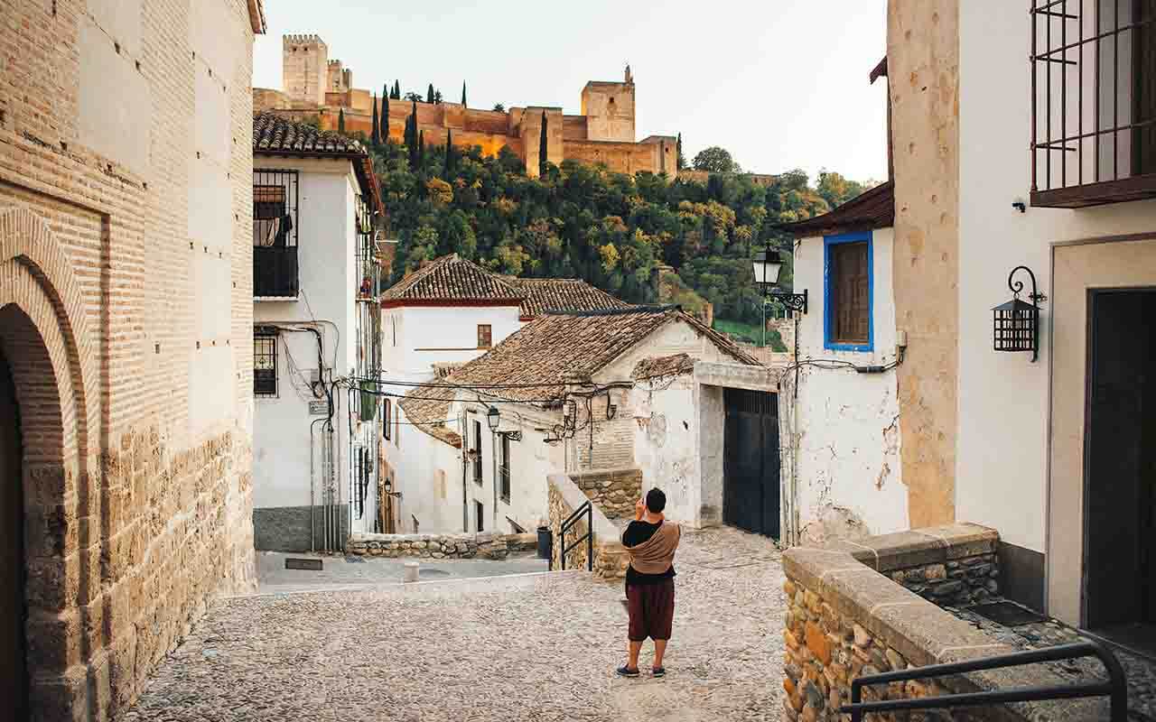 Señora en el barrio del Albaicín con La Alhambra de fondo